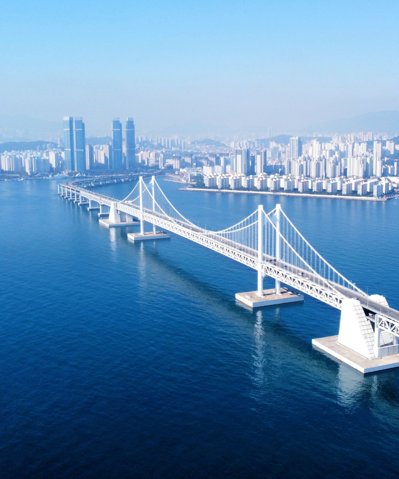 Gwangalli Beach in Busan on a clear day, with the Gwangan Bridge across the bay